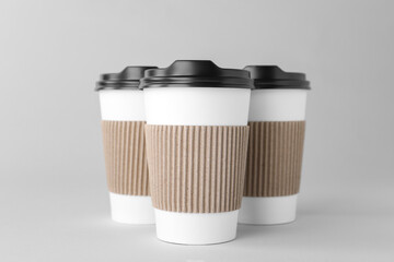 Paper cups with black lids on light grey background. Coffee to go