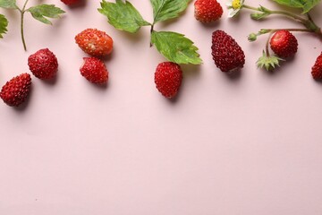 Many fresh wild strawberries and leaves on beige background, flat lay. Space for text