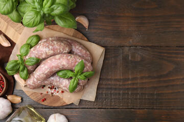 Raw homemade sausages and different products on wooden table, flat lay. Space for text