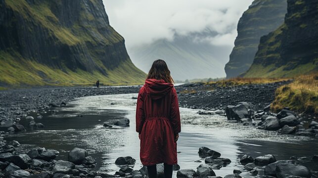Rear view of woman traveling with backpack looking at amazing waterfall in the forest