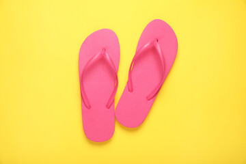 Stylish pink flip flops on yellow background, top view