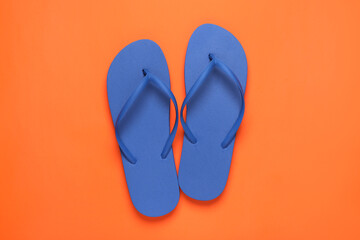 Stylish blue flip flops on orange background, top view