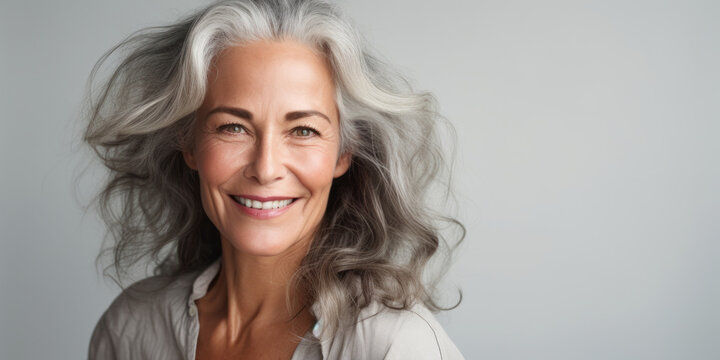 Close up beautiful female with smooth healthy face skin. Gorgeous aging mature woman with long gray hair and happy smiling. Beauty and cosmetics skincare advertising concept
