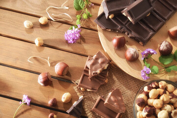 Chocolate bar with hazelnuts and leaves on white table