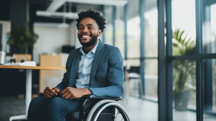 Happy young man with disability sitting in wheelchair in office - obrazy, fototapety, plakaty