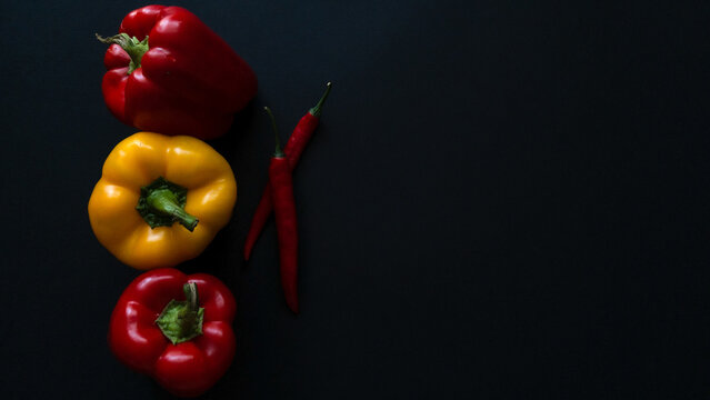 Bulgarian and chili peppers isolated on a dark background. Fresh vegetables Three sweet red, yellow and green peppers. vegan food concept. healthy eating
