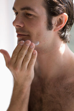 Close up of young man applying moisturizer
