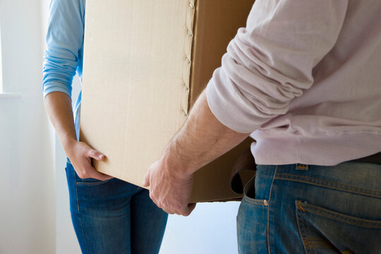 Close up of a couple hands carrying cardboard box
