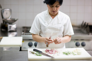Woman chef peeling garlic with a knife
