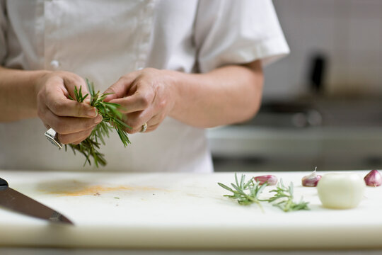 Close up of a chef hands plucking a rosemary twig
