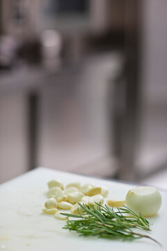 Close up of rosemary twigs with onion and garlic cloves
