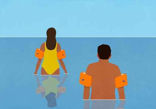 Couple in water wings wading in ocean water
