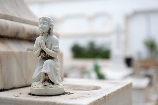 Vista de un &aacute;ngel rezando en la tumba de un cementerio el d&iacute;a de Todos los Santos.