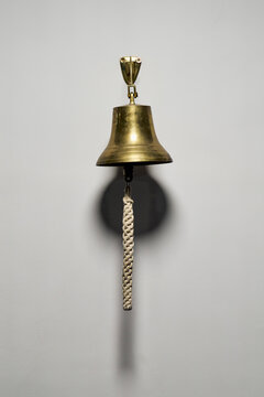 Brass bell with rope pull hanging on wall
