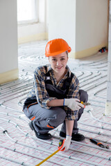 Portrait of woman worker which is installing underfloor heating system. Warm floor heating system