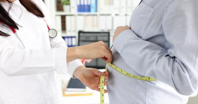 Gynecologist measures abdominal circumference with centimeter. Belly growth rules during pregnancy concept