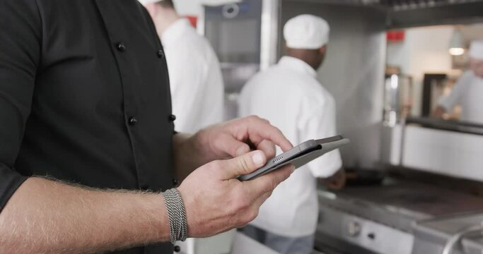 Caucasian male chef using tablet in kitchen, slow motion