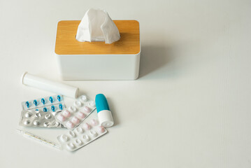 Illness concept. Top view photo of medicines nasal and throat spray bottles pills blister thermometer and paper napkins on isolated background