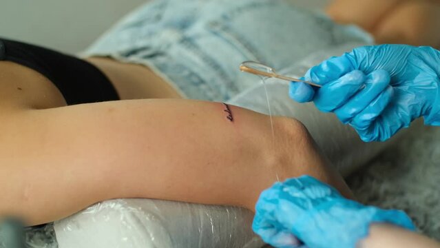 The tattoo artist applies sedative after tattoo on arm. Skin care after tattooing in studio. Body art concept close up