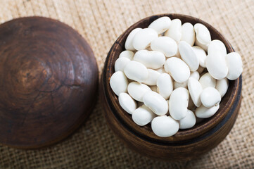 Wooden bowl full of raw white organic beans, ingridient for delightful legume-based dish