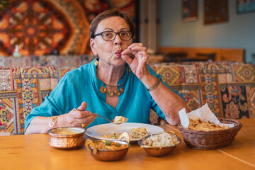 tourist senior woman telling that the food is delicious in colorful indian restaurant