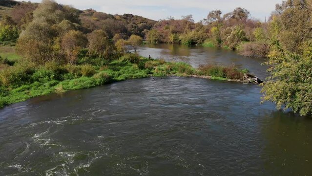 Flying along a beautiful river with rapids. A fisherman on a river with rapids catches a spinning rod in the morning in early fall.