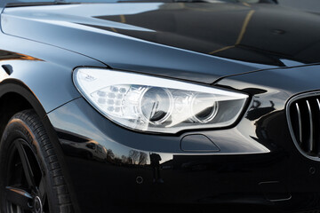 Black luxury automobile with white headlights and chrome grille on bumper. Led elements for day and night lightning in exterior of new auto