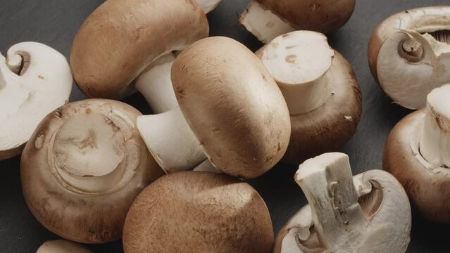 Ripe royal champignon mushrooms with slices of champignons slowly move in the frame on a gray stone table. Nice vegetable background for your projects. Macro video shooting.