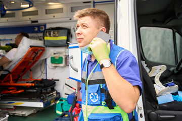 Paramedic communicates on a mobile phone near an ambulance