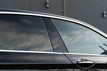 Exterior of executive luxury car of black color with tinted windows standing at parking outdoors....