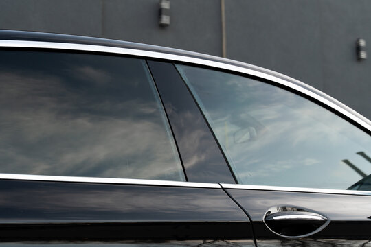 Exterior of executive luxury car of black color with tinted windows standing at parking outdoors. Modern design of expensive automobile