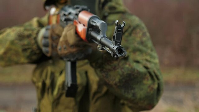 Close-up of a soldier in a military camouflage uniform aiming a sniper rifle, rifle muzzle close-up. Military conflict. Airsoft.