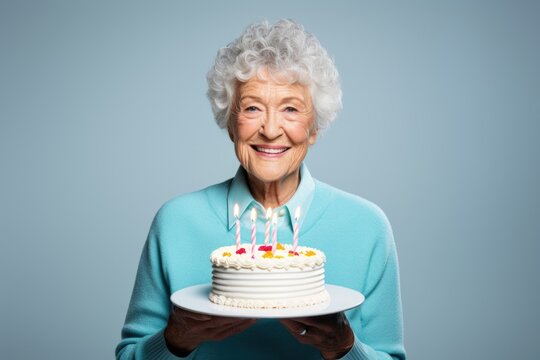 A woman holds a cake with lit candles, ready for a birthday celebration. This image can be used to depict joyous occasions and celebrations.
