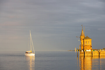 Konstanz on Lake Constance, harbor entrance with lighthouse, ships, reflections in the orange sunset