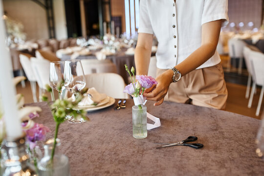 cropped view of florist decorating festive table with flowers for special occasion in event hall