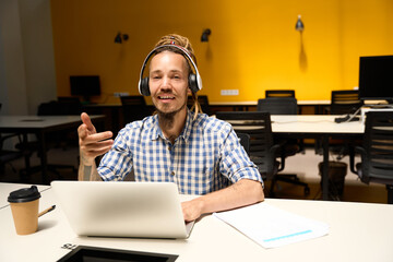 Informal man in plaid shirt communicates online at office desk