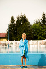 A seven-year-old boy of European appearance poses and makes faces near the pool.