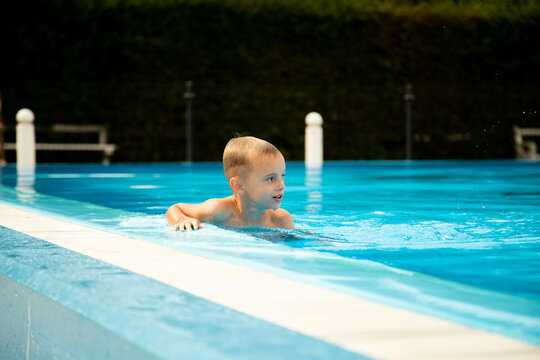 A seven-year-old boy of European appearance poses and makes faces near the pool.