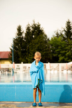 A seven-year-old boy of European appearance poses and makes faces near the pool.