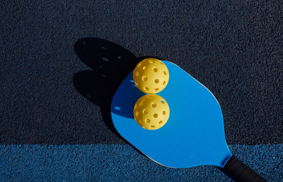 Pickleball paddle and balls on court, shot directly from above in flat lay style