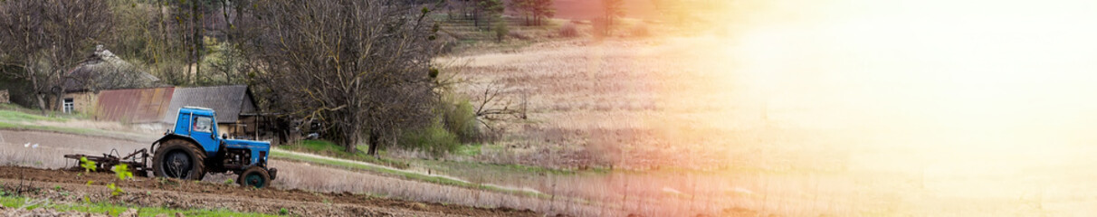 old blue tractor with plow on field and cultivates soil. Preparing the soil for planting vegetables...
