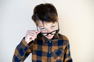 cool young boy wearing black glasses in front of brown background