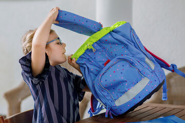 Happy smiling girl preparing for school her backpack. First day of school. Back to school concept....