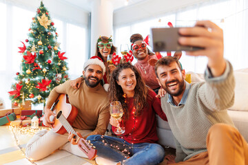Friends having fun taking selfies while celebrating Christmas at home