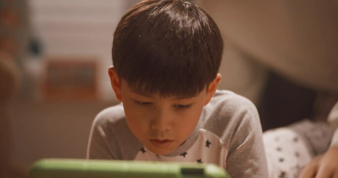 침실에서 태블릿으로 비디오 게임을 하는 아들과 아들 방에 들어온 아빠