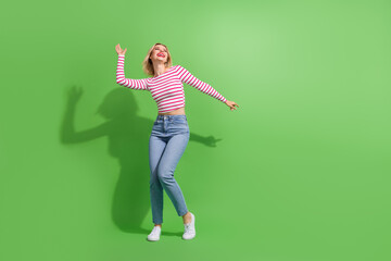 Full length photo of cute dreamy lady wear striped top having disco fun looking empty space isolated green color background