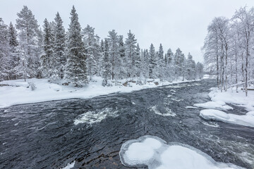 Winter in Finland; landscape with river and snow covered boreal forest
