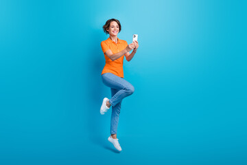 Full length photo of adorable optimistic woman wear orange t-shirt stylish jeans jumping make...