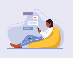 dark-skinned girl sits in a bag chair and sends a message