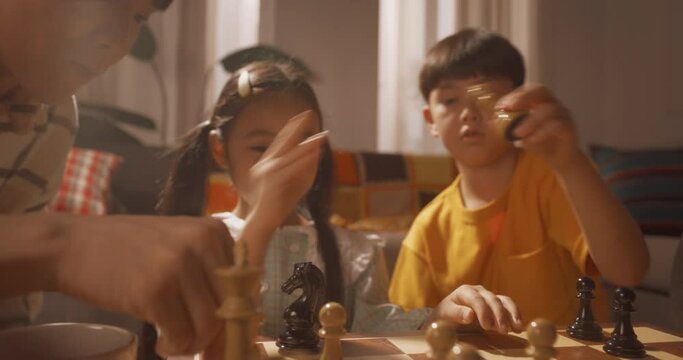 거실에서 아빠와 아들이 체스 게임을 하고 엄마와 딸이 옆에서 도와주는 가족의 상반신 영상